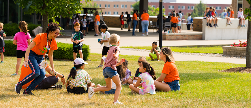 A graphic that features children and staff outside sitting in the grass with one child and one staff member running around.